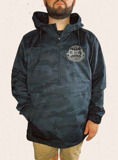 Black camo Independent Trading Company Hooded Anorak Jacket embellished with a world logo containing the words WOLF DEN WARES, LISTEN. EXPLORE. CREATE.